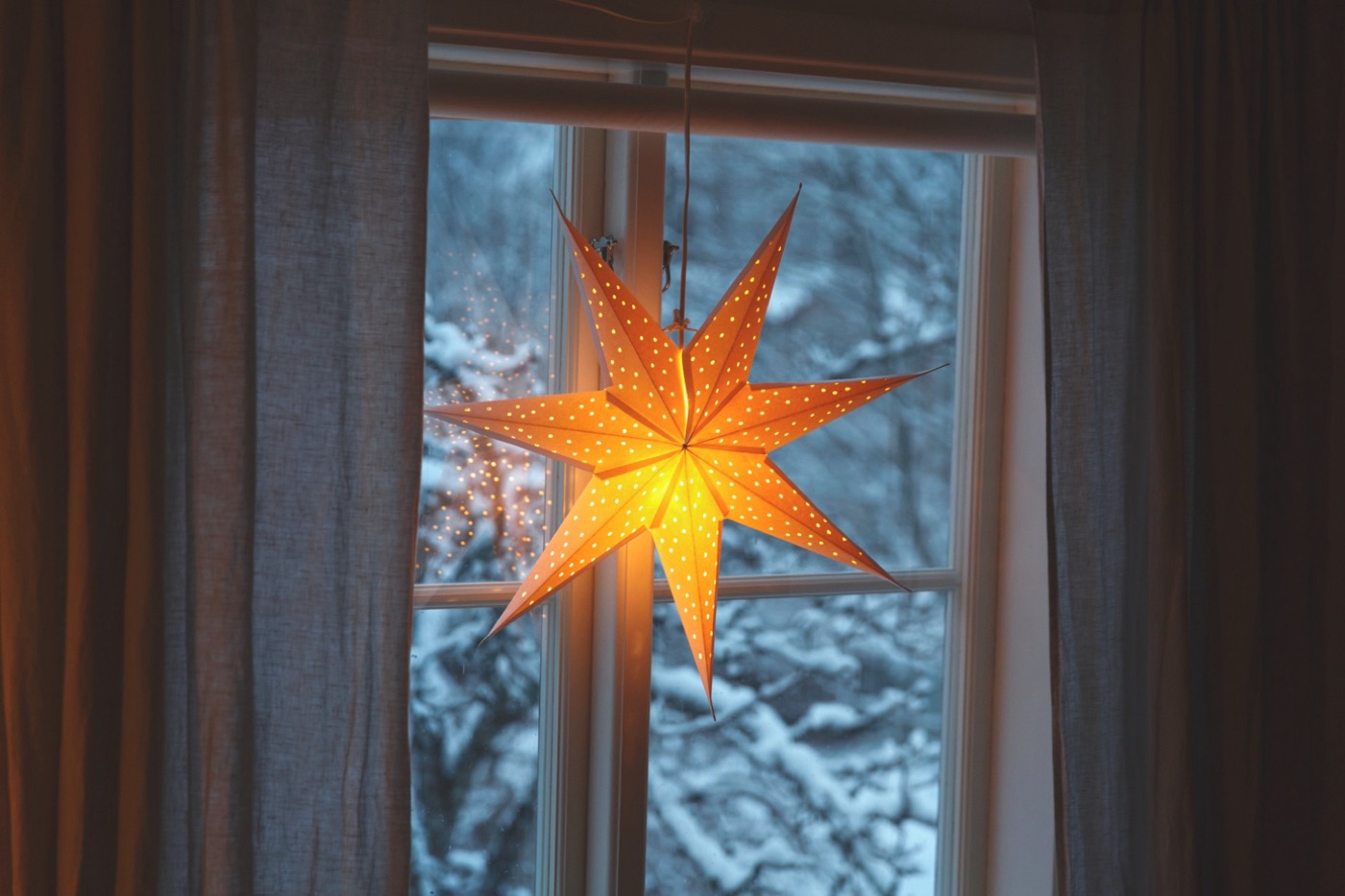 En adventsstjärna som lyser i ett svenskt hemfönster